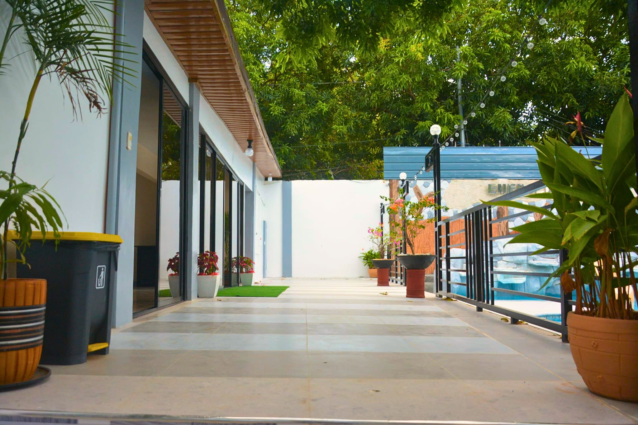 A cozy outdoor seating area with modern design elements, surrounded by plants and a black metal railing.