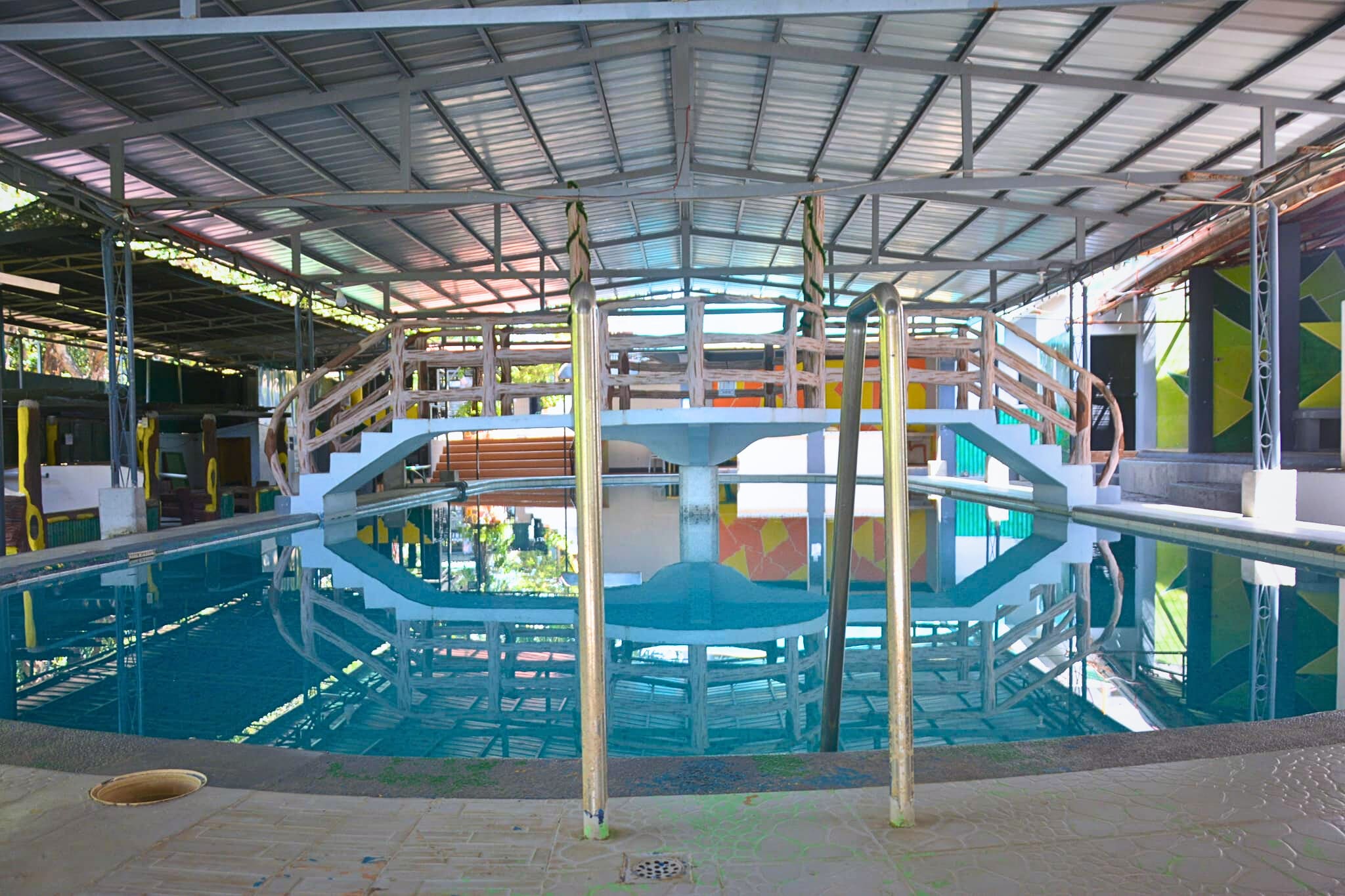 A cozy outdoor seating area with modern design elements, surrounded by plants and a black metal railing.